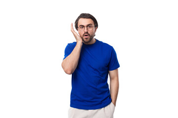 Wall Mural - young shocked european brunette man with beard dressed in blue t-shirt on studio background