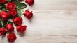 Red roses with green leaves on a wooden background with copy space.