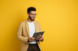© RJ.RJ. Wave - happy smiling handsome man with tablet on bright yellow solid background with copy space