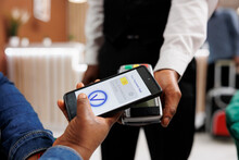 Close Up Of Hotel Guest Paying With Digital Wallet, Holding Phone Making Mobile Payment. Customer Using Nfc Technology To Pay With Smartphone Via Pos Terminal, Going Cashless In Hospitality Industry