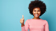 Happy African American woman giving thumbs up on a solid background