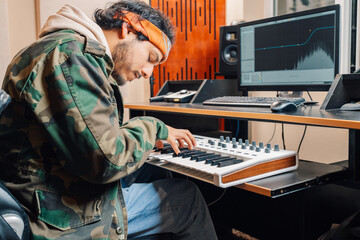 Young man playing electronic piano while recording music at home