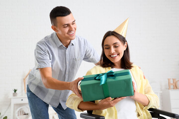 Wall Mural - Young man with his wife in wheelchair celebrating Birthday at home