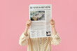© Pixel-Shot - Young woman with newspaper on pink background