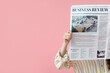 © Pixel-Shot - Young woman reading newspaper on pink background