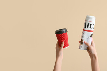 Wall Mural - Woman with rolled newspaper and coffee cup on beige background