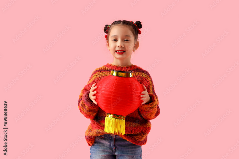 Cute little Asian girl on pink background. Chinese New Year celebration