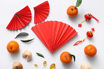 Composition with paper fans, tangerines and Chinese symbols on white background. New Year celebration