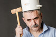 A crazy man with a saucepan on his head tries to find a thought with a hammer.