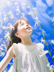 Wall Mural - A beautiful little girl in a bluebell flowers field against a blue sky