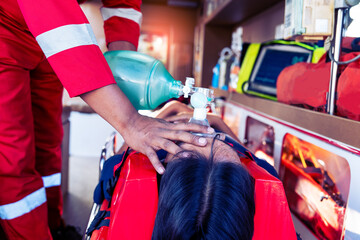 male rescue worker saves the life of an injured person while lying on a board wearing a collar and using a ventilator on the ambulance.