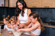 © dvulikaia - Young mother cooks sweet cottage cheese pie with her daughters. Mom teaches her daughters to cook.