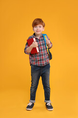 Sticker - Cute schoolboy with backpack and book on orange background