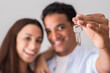 Close up of new home keys and young interracial couple smile and show the property - new life mortage house buyers people concept - happy youth family in love and relationship showing key