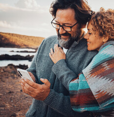 Romantic couple of traveler tourist use mobile phone together with love and relationship in outdoor leisure activity. Desert and country side background with wind turbine windmills. Concept of travel