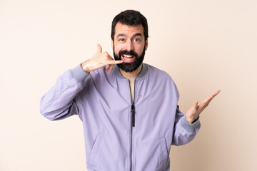 Wall Mural - Caucasian man with beard wearing a jacket over isolated background making phone gesture and doubting