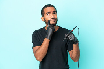 Wall Mural - Tattoo artist Ecuadorian man isolated on blue background having doubts while looking up