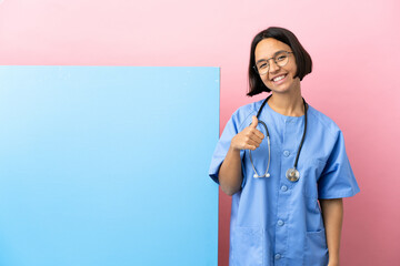 Wall Mural - Young mixed race surgeon woman with a big banner over isolated background giving a thumbs up gesture