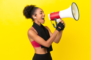 Wall Mural - Young African sport woman isolated on yellow background shouting through a megaphone