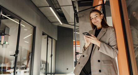 A young female marketer in the office uses a phone and a business application to communicate with a client. An employee of the company in a jacket.