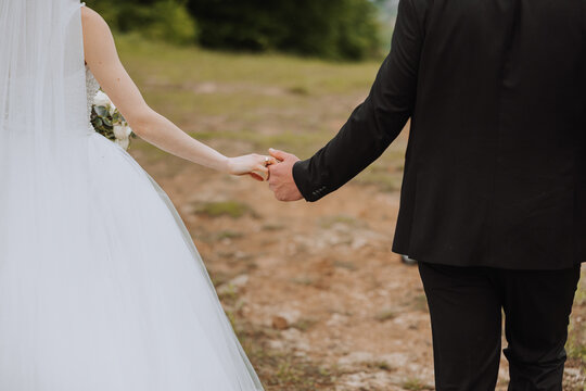 The groom holds the bride's hand. Cropped photo. Groom in a black suit. Details