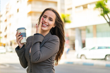 Poster - Young woman holding a take away coffee at outdoors whispering something