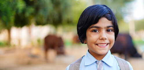 Smiling student girl wearing school backpack and holding exercise book. Portrait of happy asian village girl in front of pets. Face of smiling school girl looking at camera.