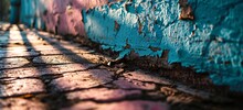 A Pink And Blue Brick Wall With Peeling Paint And A Leaf On The Ground