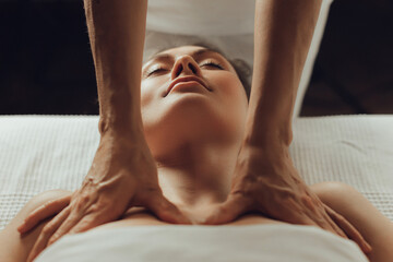 Wall Mural - Hands of female chiropractor massaging shoulders of young woman lying on massage table. Concept of physical therapy treatment ,neck pressure point