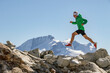 © ADDICTIVE STOCK - Runner in a green jacket leaping between rocks in high altitude