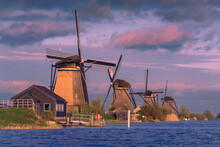 Sunset Over A Serene Dutch Landscape With A Row Of Historic Windmills And Waterfront Houses At Kinderdijk