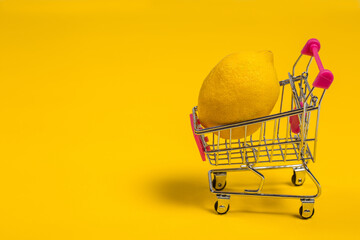 Lemon in shopping cart on yellow background