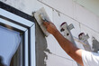 Construction worker applying top layer of plaster next to newly installed window closeup detail during house construction