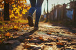 A person is walking down a road covered in fallen leaves. This image can be used to depict autumn, nature walks, or peaceful outdoor scenes
