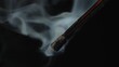 Macro shot of a black charred match and clouds of white smoke. Burned extinguished wooden match on dark studio background.