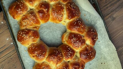 Poster - freshly baked yeast dough bread on a baking pan is placed on a wooden kitchen table top, vertical video