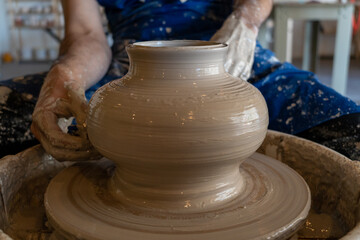 Potter throwing a pot on the wheel in a studio