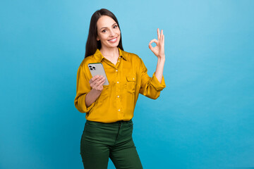 Sticker - Photo of cool confident lady wear yellow shirt showing okey sign reading sms modern device empty space isolated blue color background