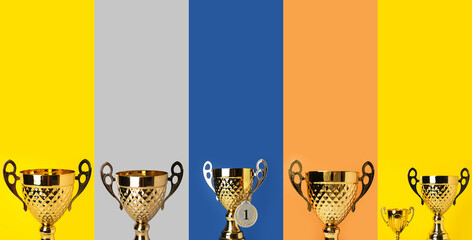 collage of golden trophy cups and medal on color background