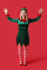 Wall Mural - Emotional young woman in elf costume on red background