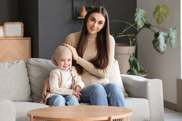 Wall Mural - Little girl after chemotherapy with her mother sitting on sofa at home