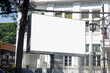 Large horizontal blank advertising poster billboard mockup in front of building in urban city