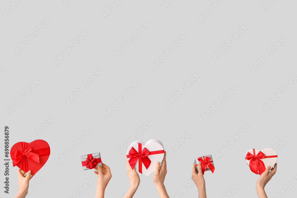 Female hands with gift boxes on grey background. Valentine's Day celebration