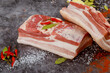 Two pieces of raw pork belly with garlic and bay leaves.
