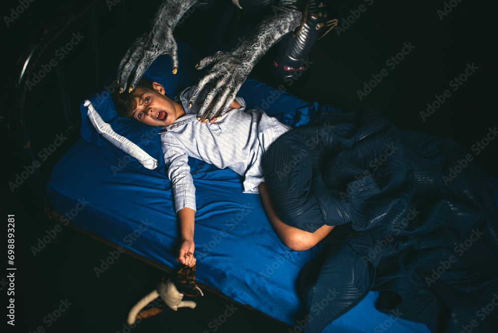 Scared boy in bed at night screaming while being attacked by a boogyman ...