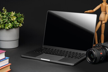 Canvas Print - Open laptop with wooden mannequin on table against black background