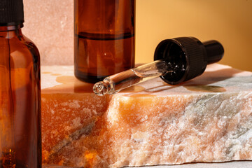 Cosmetic serum in an amber glass bottle with dropper lid with granite stone for composition