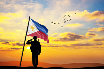 Silhouette of a soldier with the Philippines flag stands against the background of a sunset or sunrise. Concept of national holidays. Commemoration Day.