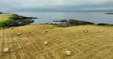 A Drone Flying Over An Agricultural Field Full Of Hay Bales Against The Sea 4k 