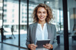 © Uzair - Portrait of successful and happy businesswoman, office worker smiling and looking at camera, working inside modern office.